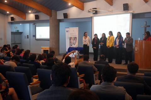 Un grupo de presentadores se encuentra en un auditorio realizando una exposición frente a una audiencia.