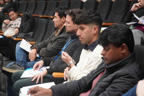 Un grupo de hombres sentados en una sala de conferencias prestando atención a la presentación.
