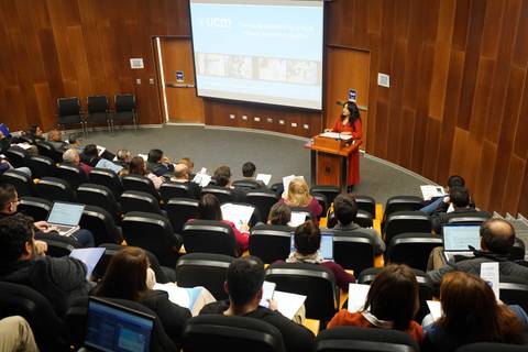 Una expositora presenta en un auditorio lleno de personas que están tomando notas.