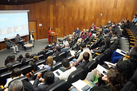 Una charla en un auditorio con un público atento y un presenter en el escenario.