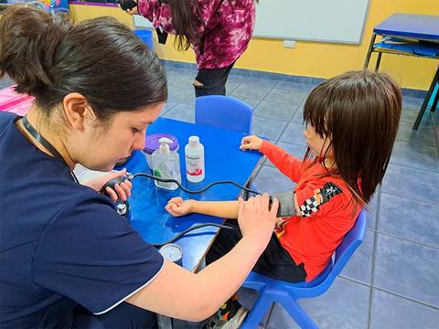 Una enfermera está tomando la presión a un niño en un aula.