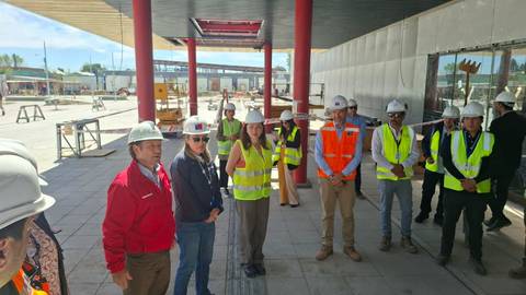 Un grupo de personas con cascos y chalecos de seguridad se reúne en un sitio de construcción.
