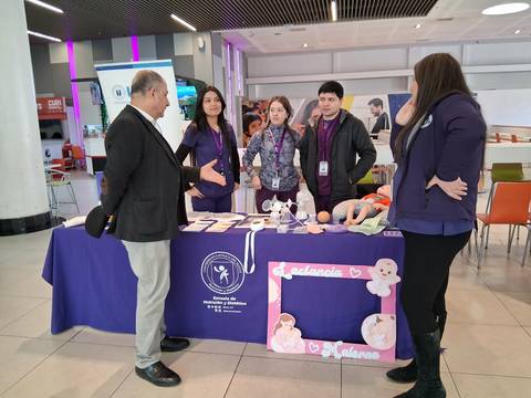 Un grupo de jóvenes presenta un stand con materiales educativos en una feria escolar.