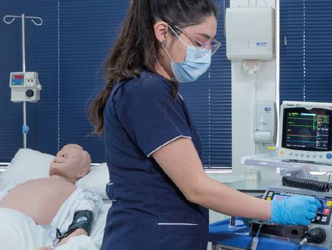 Una estudiante de enfermería está utilizando un monitor en un simulador médico.