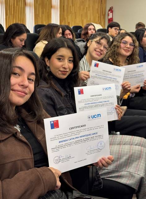Un grupo de estudiantes sonríe felices mostrando sus certificados en un evento académico.