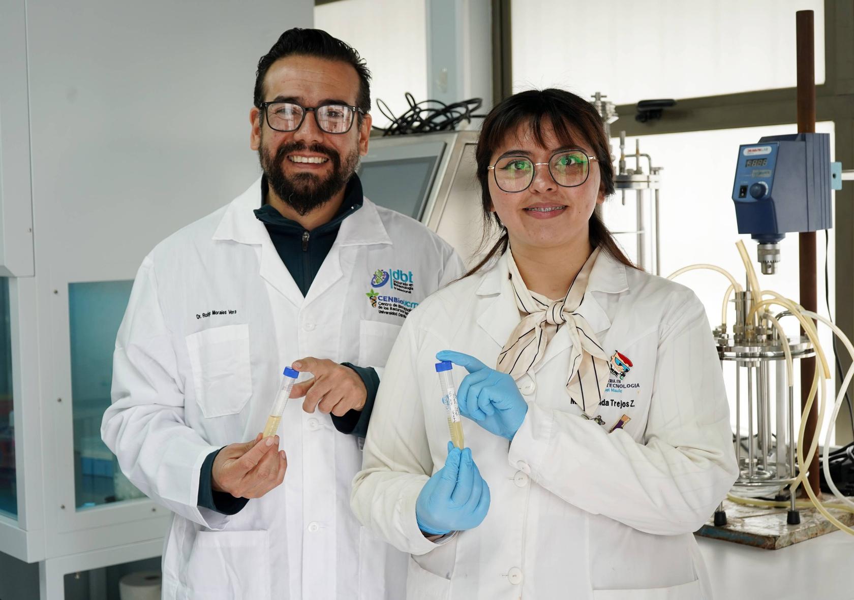 Dos profesionales con bata de laboratorio sosteniendo tubos de ensayo en un laboratorio chileno.