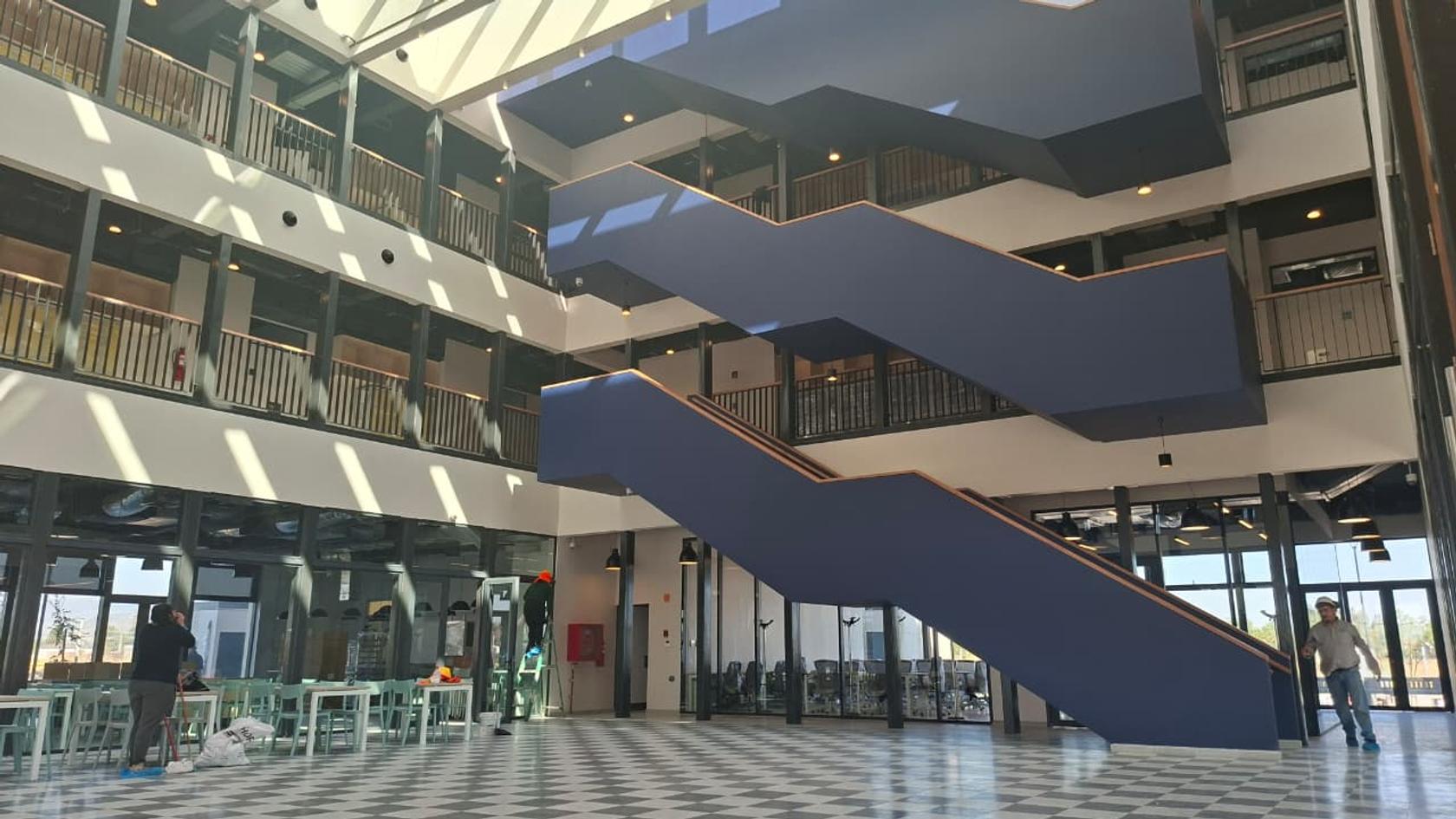 Vista de un moderno edificio con escaleras y luz natural entrando por el techo.