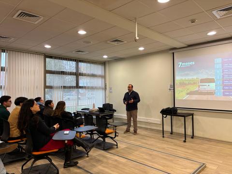 Un profesor presenta un tema frente a un grupo de estudiantes en un aula moderna.