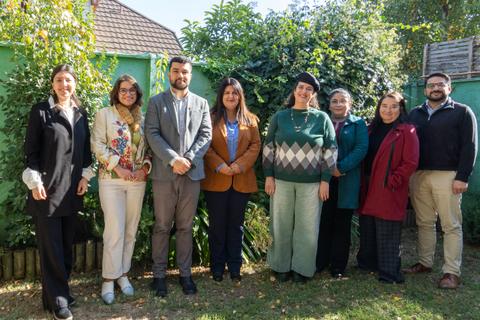 Un grupo de personas sonrientes se reúne en un jardín verde.