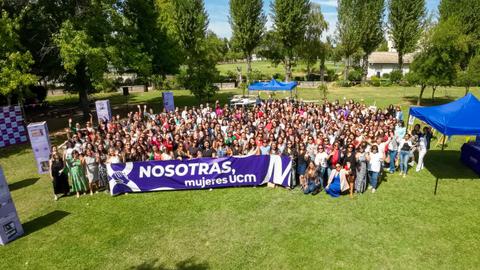 Un gran grupo de mujeres se reunió en un evento en un parque durante un día soleado.
