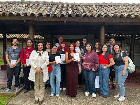 Un grupo de personas posando en un entorno al aire libre, sosteniendo documentos en un evento comunitario.