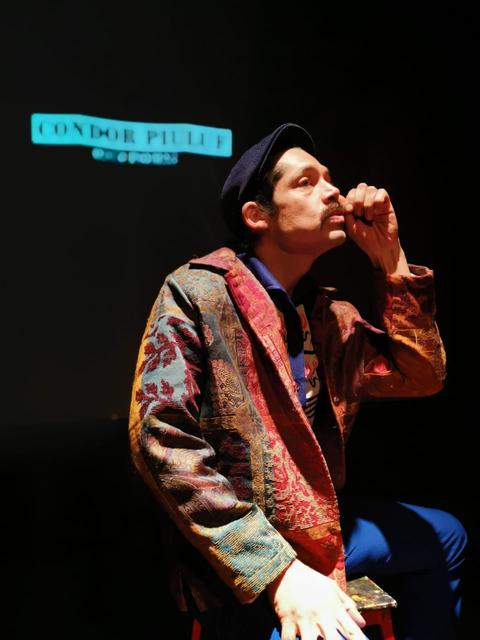 Un hombre estilizado con un abrigo colorido y un gorro piensa mientras se encuentra frente a una proyección.