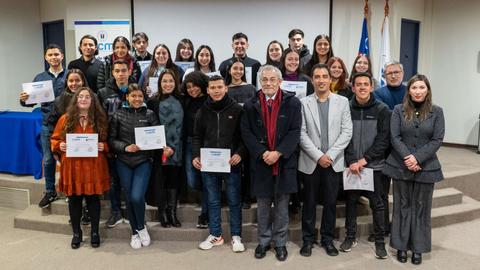 Un grupo de personas sonrientes posando con diplomas en un evento de ceremonia de entrega de certificados.