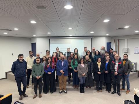 Un grupo grande de personas posando en una sala de clases.