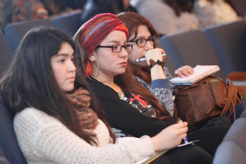 Tres mujeres sentadas en un evento, escuchando atentamente.