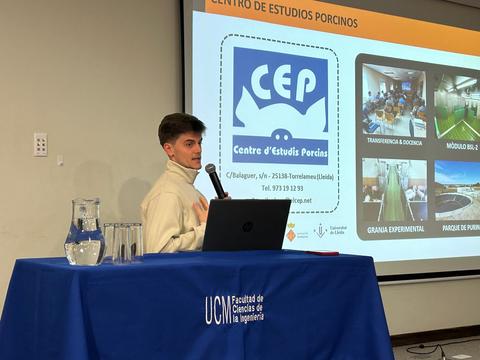 Un joven presentando en una charla sobre el Centro de Estudios Porcinos en un auditorio.