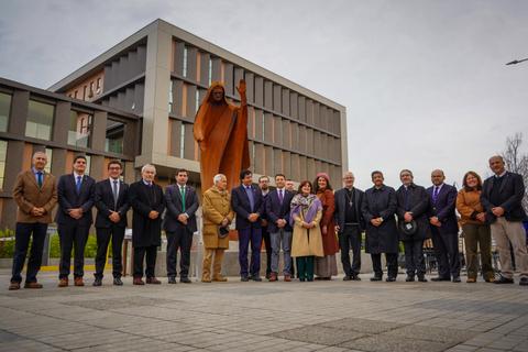 Un grupo de personas posa frente a una escultura en un día nublado en Chile.