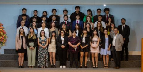 Un grupo grande de jóvenes posando en un evento formal.