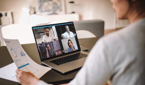 Una persona participando en una videoconferencia con varias pantallas en su computador.