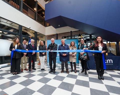 Una ceremonia de inauguración con varias personas sosteniendo un lazo azul en un espacio moderno.