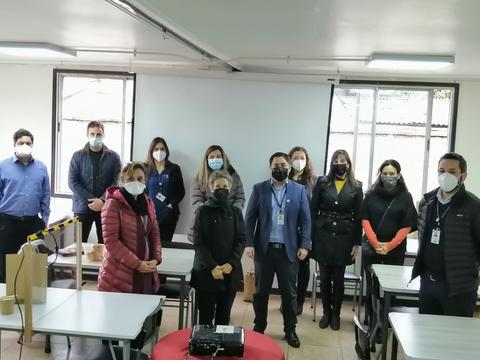 Un grupo de personas posando en un aula con mascarillas durante un evento.