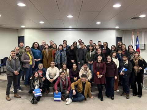 Un grupo grande de personas posando juntas en un auditorio.
