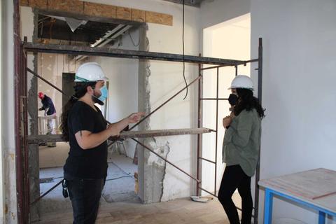 Dos personas conversan en un espacio en construcción.
