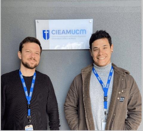 Dos personas posando ante un cartel de una universidad en Chile.