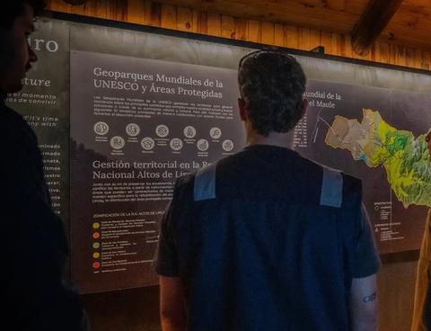 Un grupo de personas observa un panel informativo sobre geparques y áreas protegidas en Chile.