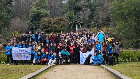 Un grupo grande de personas posando con pancartas en un paisaje natural.