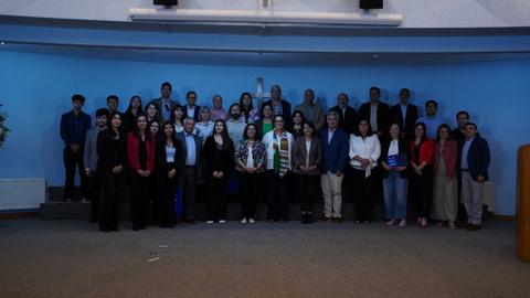Un grupo grande de personas posando juntas en un ambiente interior con luces azules.