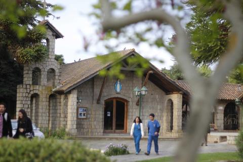 Una casa de piedra con un jardín y personas caminando cerca.
