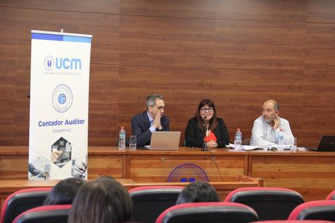 Un panel de discusión en una sala con tres presentadores frente a una audiencia.