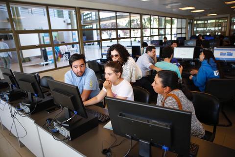 Un grupo de personas trabajando en computadoras en un aula de informática.