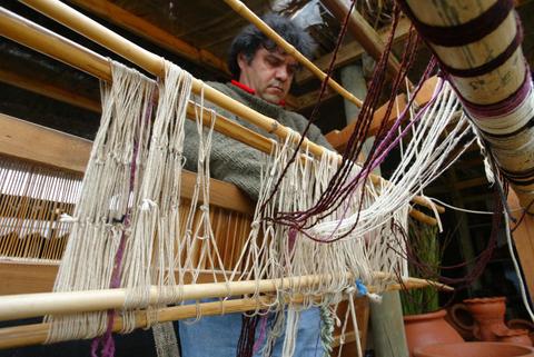 Un hombre trabaja en un telar, tejiendo hilos de diferentes colores.