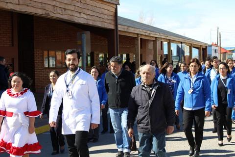 Un grupo de personas camina por un lugar al aire libre, con una mujer vestida con un traje tradicional al frente.