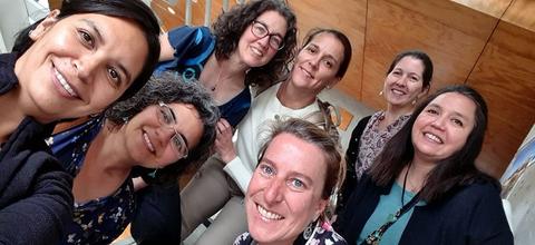 Un grupo de ocho mujeres se toma una selfie, sonriendo y posando juntas.