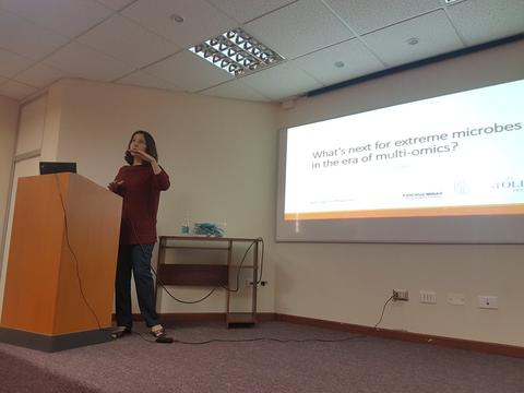 Una mujer está presentando sobre microbiología extrema en una conferencia.