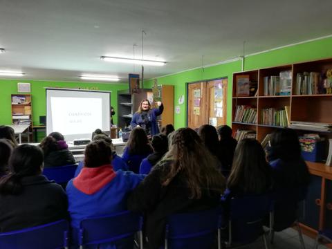 Una mujer está dando una charla frente a un grupo de personas en un aula.