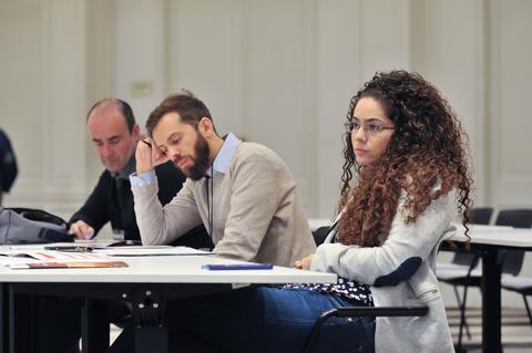 Un grupo de personas sentadas en una sala, concentradas en una actividad.