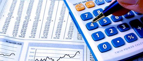 Una mano utiliza una calculadora mientras revisa gráficos y datos financieros en hojas de papel.