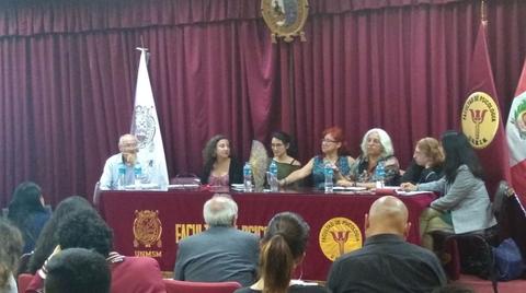 Una mesa de discusión académica con varios panelistas y un público sentado en un auditorio.