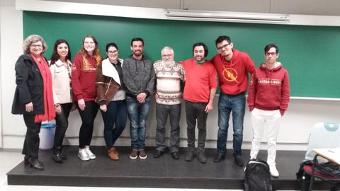 Un grupo de ocho personas posando juntas en un aula con una pizarra verde de fondo.