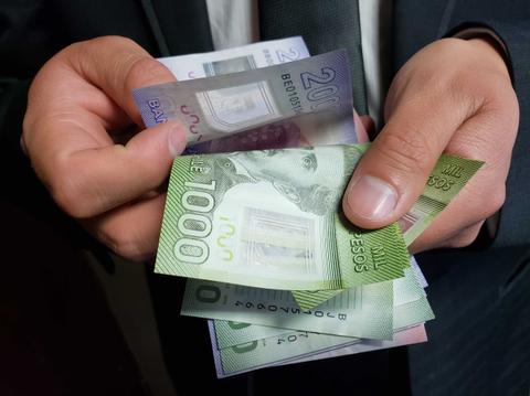 Una persona sostiene varios billetes de diferentes denominaciones en sus manos.