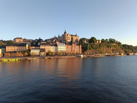 Una vista panorámica de un paisaje urbano junto al agua con edificios históricos y vegetación.