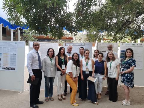 Grupo de personas posando frente a carteles informativos en un evento al aire libre.