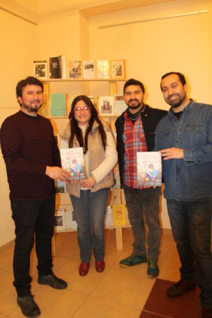 Cuatro personas posan sonrientes sosteniendo un libro en una librería.