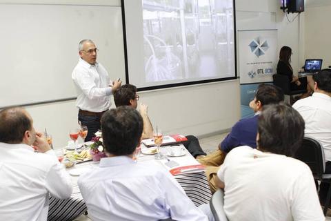 Una presentación en una sala con personas escuchando y comida en la mesa.