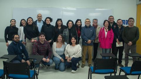 Grupo de personas posando en un aula con una pizarra blanca de fondo.