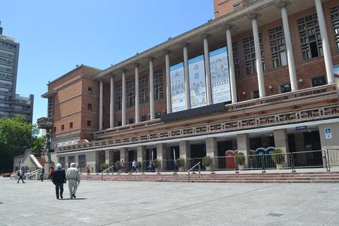 Imágen de un edificio público moderno con personas caminando en frente.